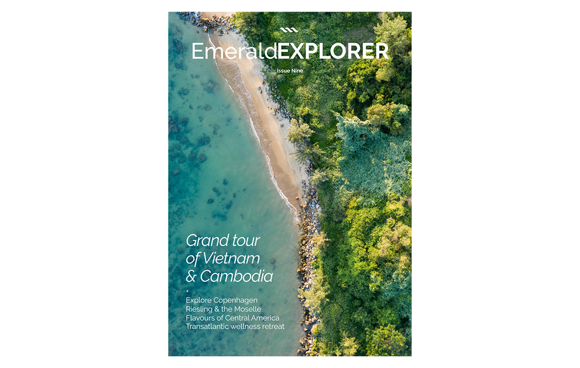 Magazine cover, with an aerial shot of the beach near a forest, with the calm blue waters