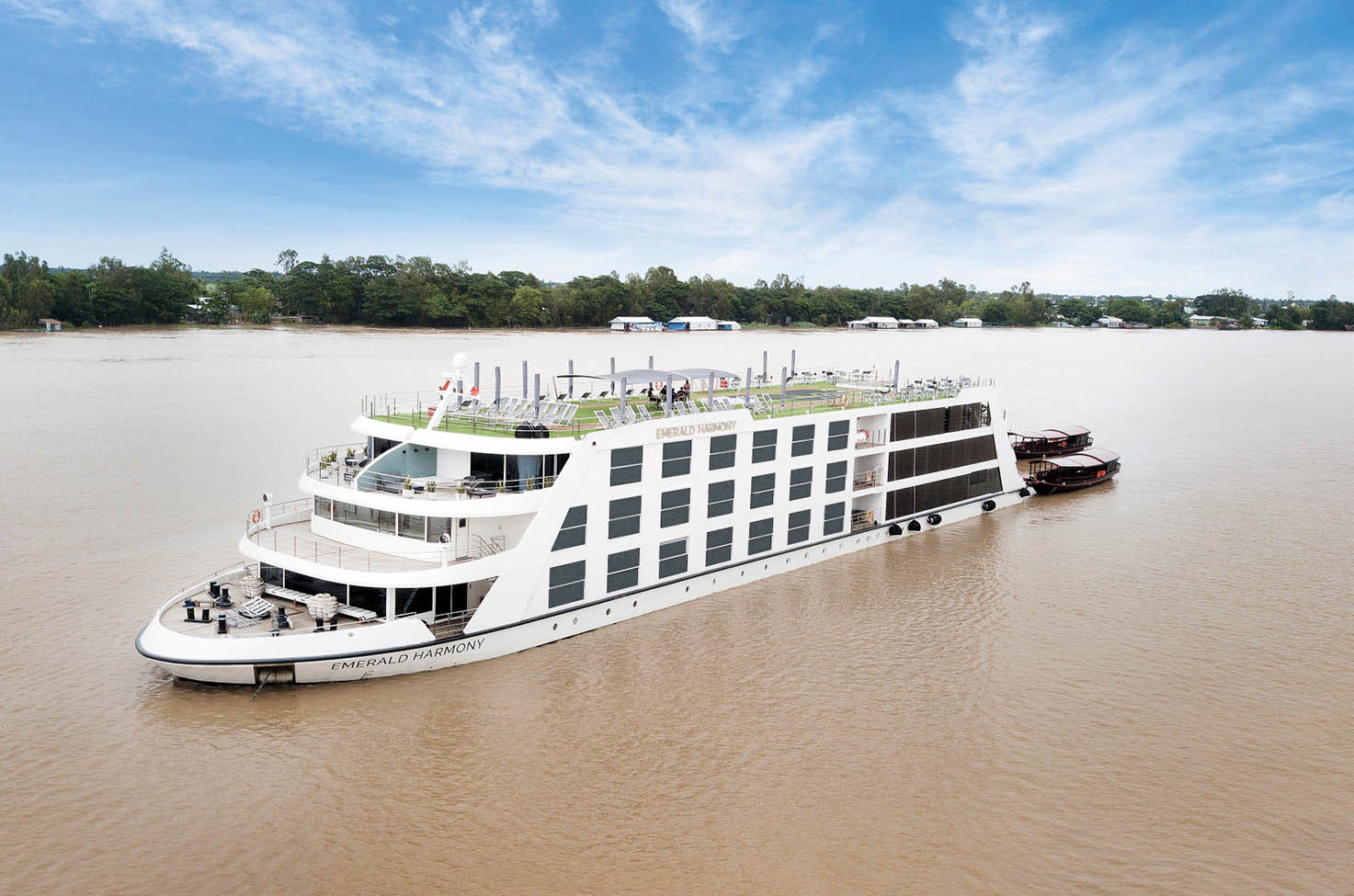 White luxury river cruise ship, the Emerald Harmony, sailing under a cloudy sky