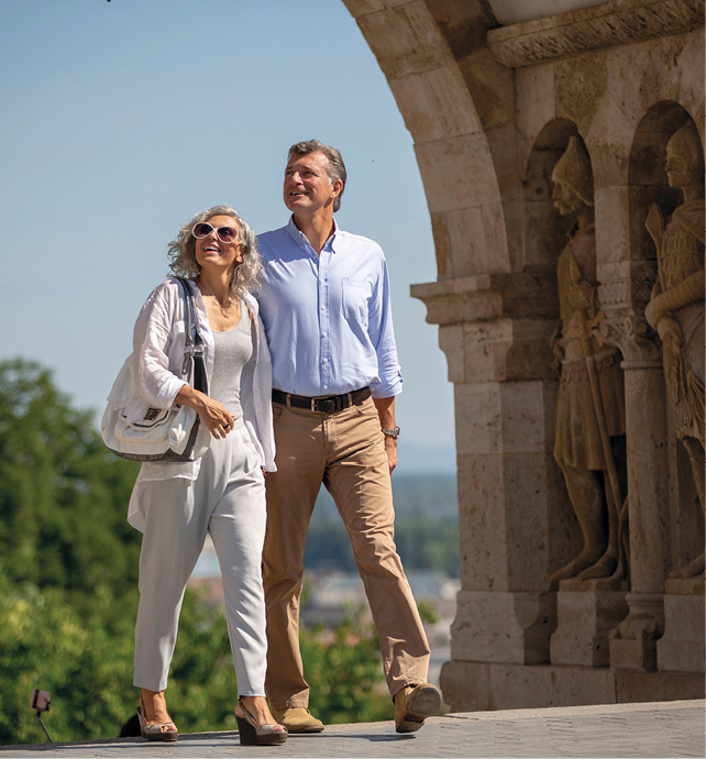 A middle-aged couple smiling and walking through Budapest on a sunny day