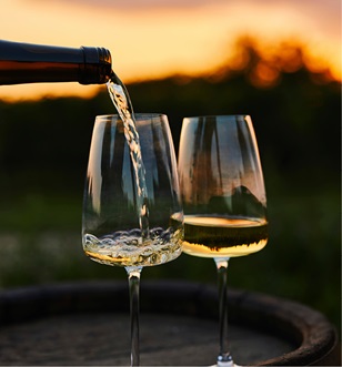 White wine being poured into two wine glasses at sunset