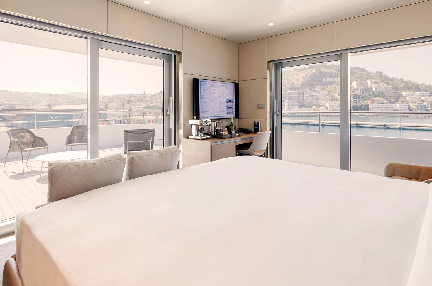 Suite on board a luxury yacht with double bed and balcony doors shown.