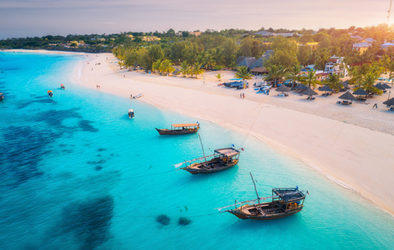 Crystal clear waters can be seen on this beach. The sand is white and the sun is setting in the background