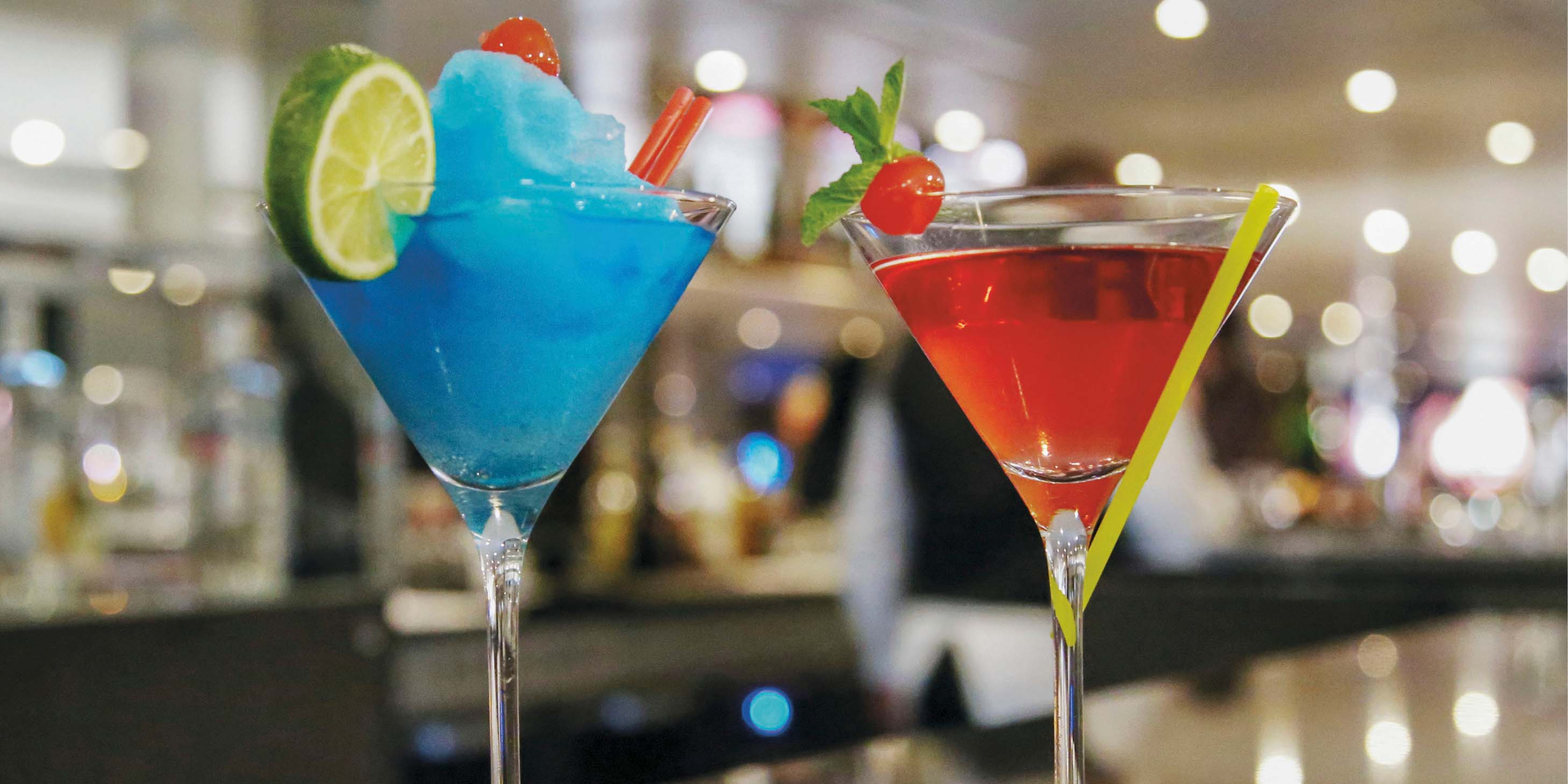 Red and blue cocktails with fruit garnishes on a bar