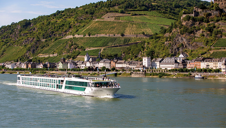 Luxury cruise ship sailing the Rhine River past a quintessential Europe town, with rolling hills in the background