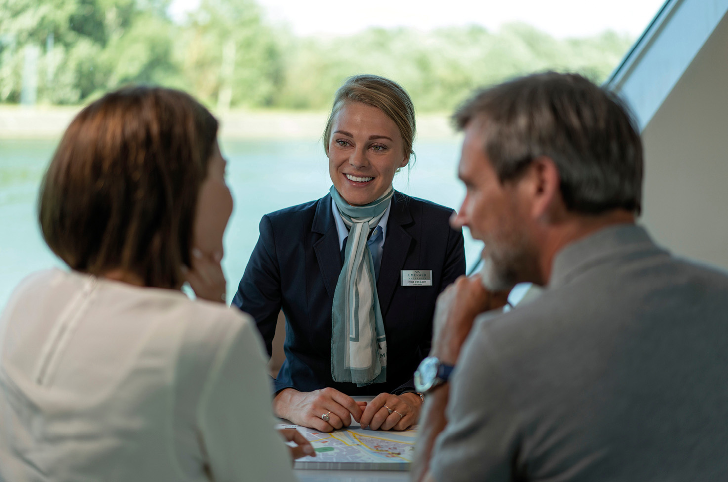Couple sat opposite a smiling professional woman, with a large window behind her