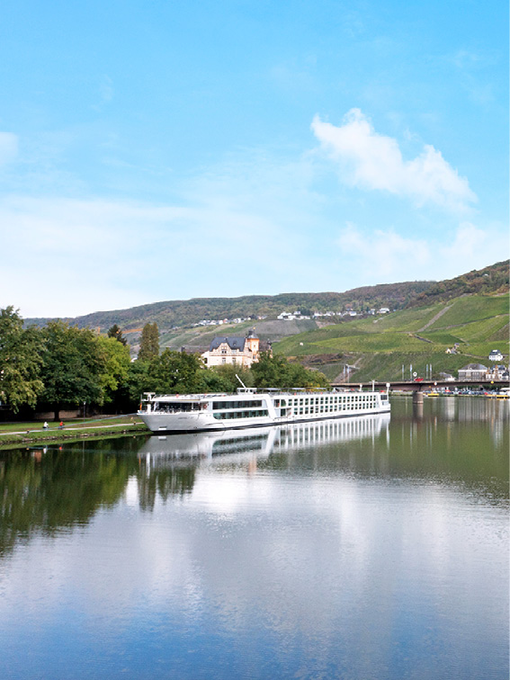 Luxury river ship docked in Bernkastel, Germany, with the landscape reflected in the water’s surface