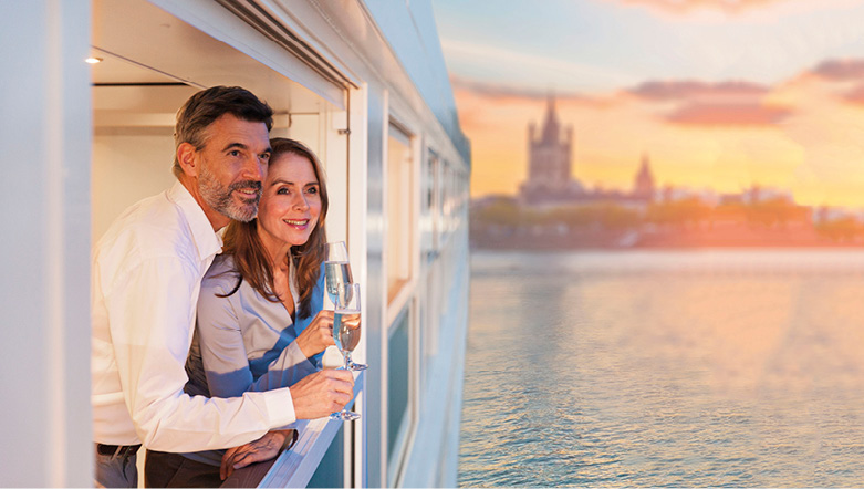 Couple enjoying a glass of Champagne whilst admiring the view on board a luxury river ship  