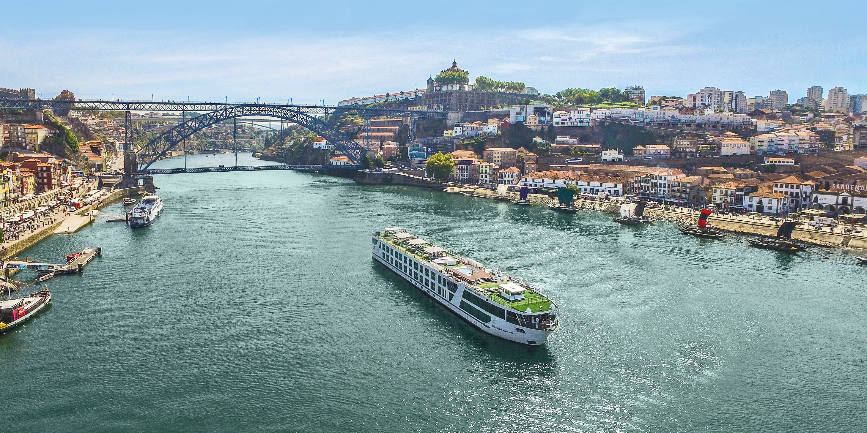 Luxury river ship sailing through Porto along the Douro River, past the Dom Luís I Bridge