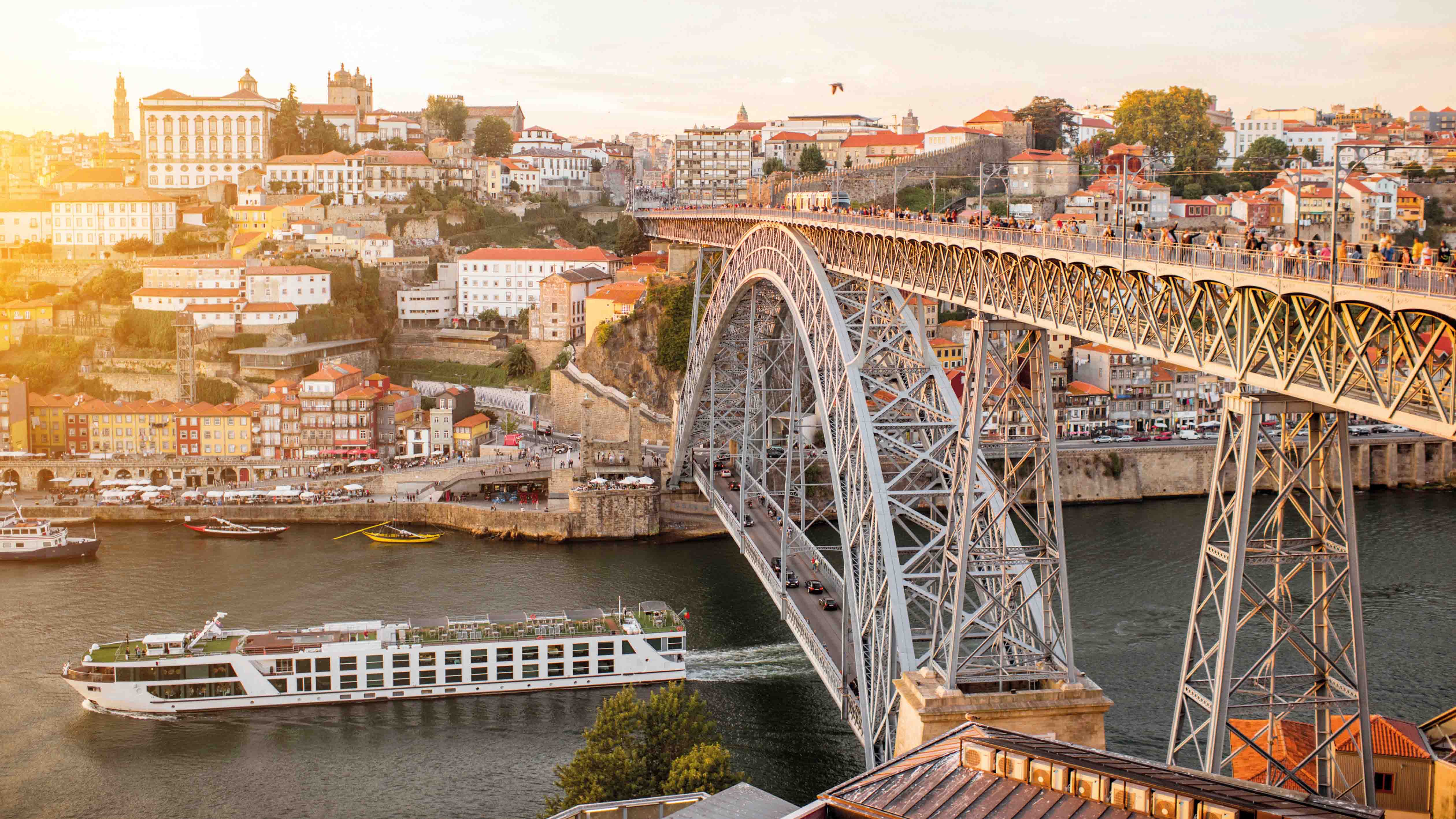 Luxury river ship sailing along the Douro River through the heart of Porto at sunrise