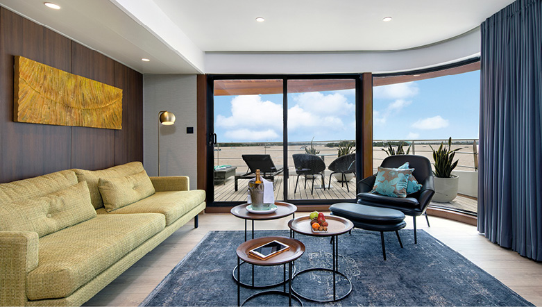 A River ship's One Bedroom Suite with large living area space and wide glass doors leading to the balcony