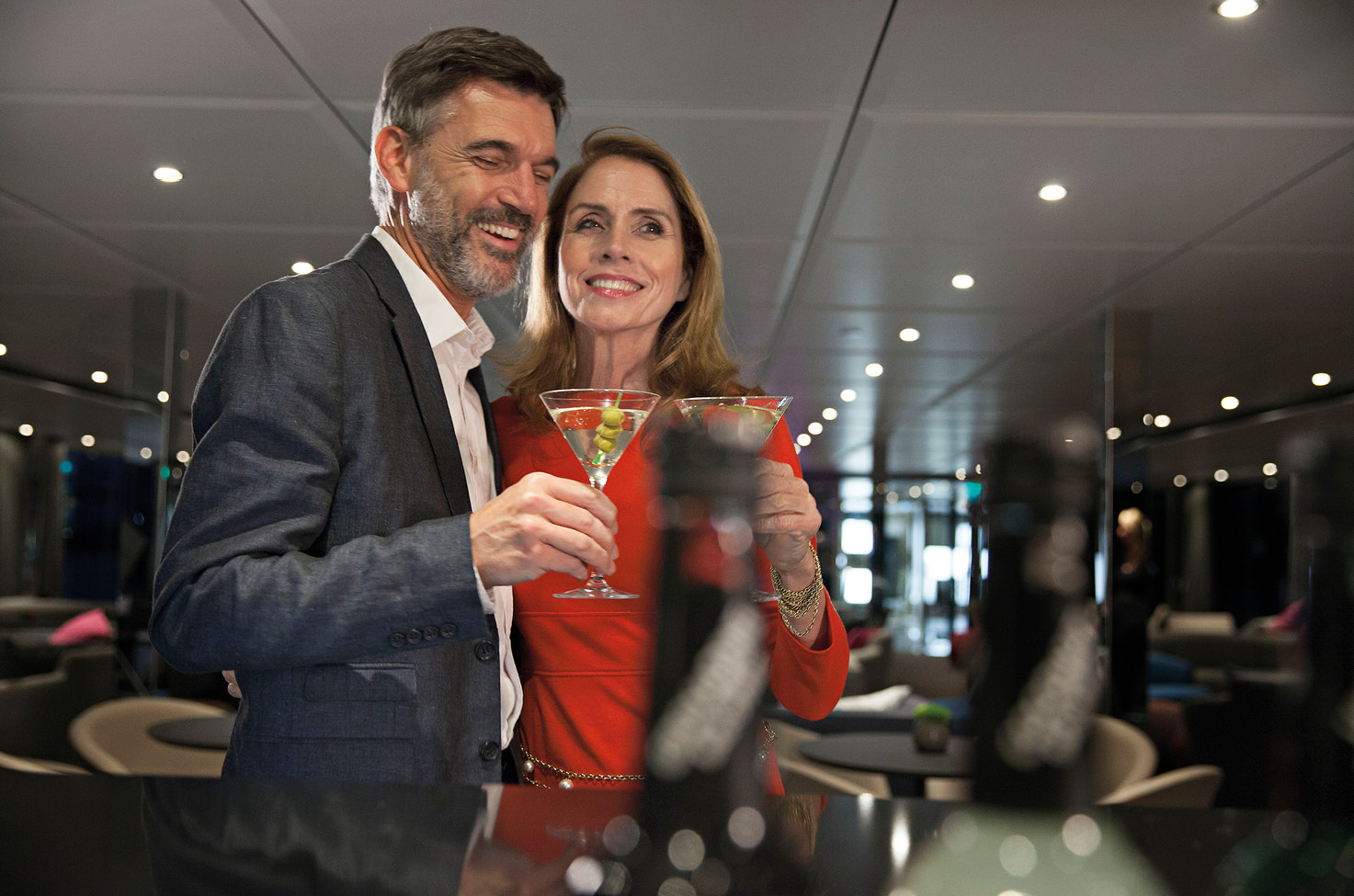 Smartly dressed man and woman smiling and enjoying cocktails in a bar lounge
