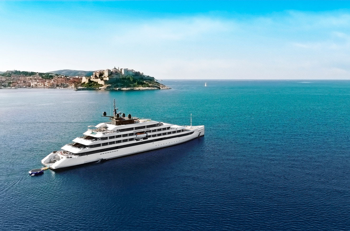 Luxury yacht on calm blue sea sailing past Corsica, under a blue, light cloudy sky 