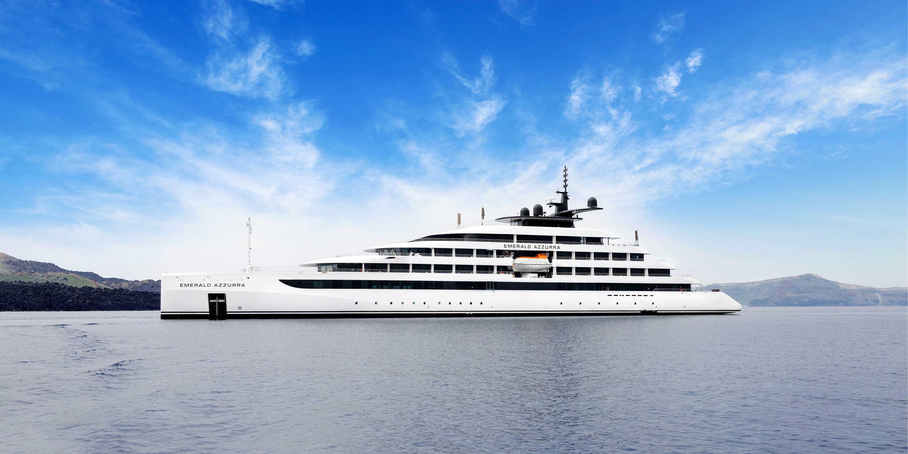 Luxury yacht sailing on a blue ocean with land seen in the distance