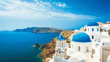 Blue-domed church of Santorini, Greece on a bright sunny day, with light cloudy sky and deep blue sea