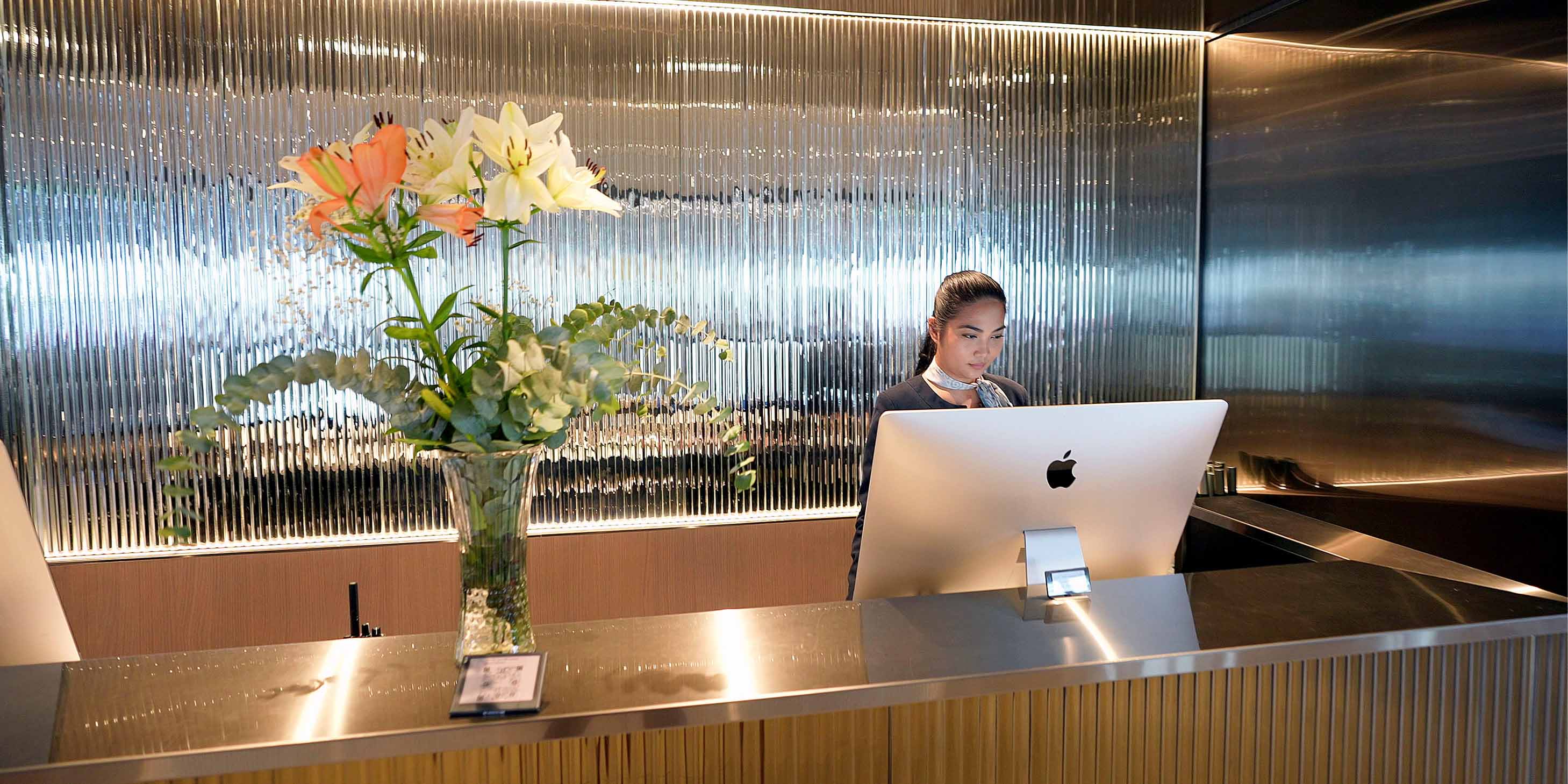A member of reception staff on board an Emerald Cruises yacht stood behind a desk looking at a computer 