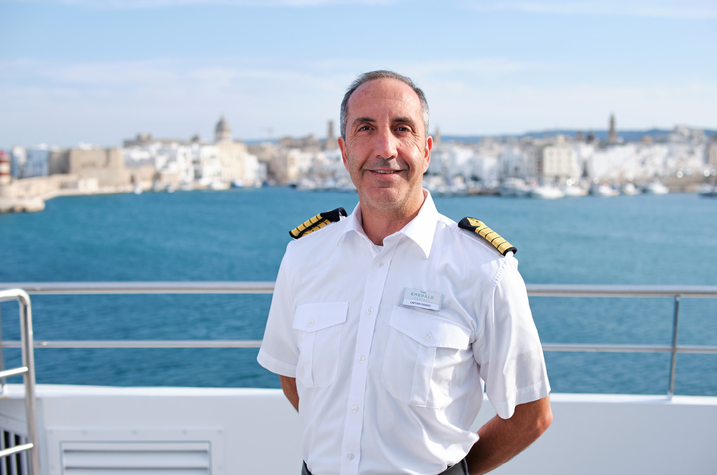 View of the deep blue sea from the balcony of a cruise ship, with hills visible through the mist in the distance   Image File Name: