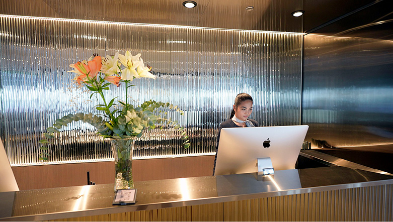 A member of reception staff on board an Emerald Cruises yacht stood behind a desk looking at a computer 